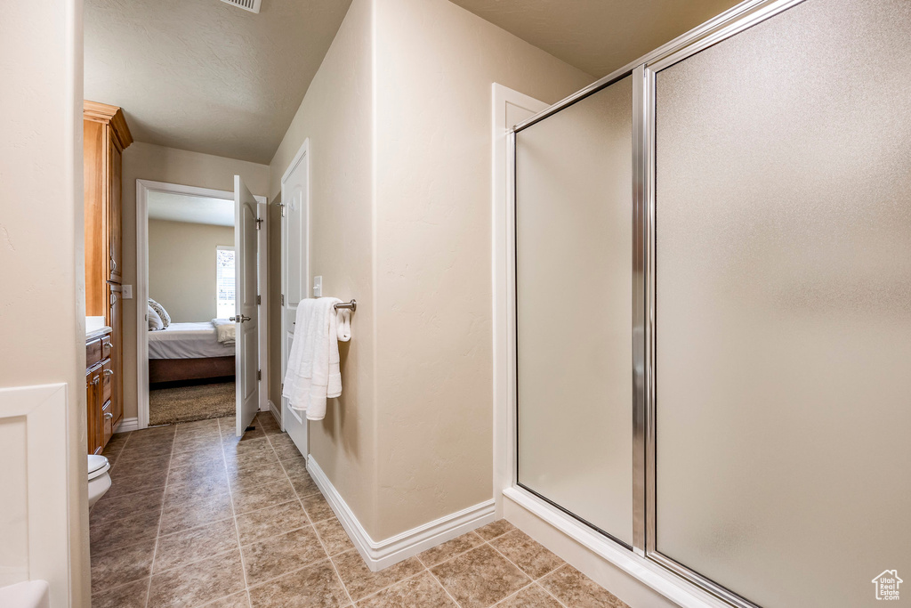 Bathroom with toilet, tile patterned flooring, and a shower with door