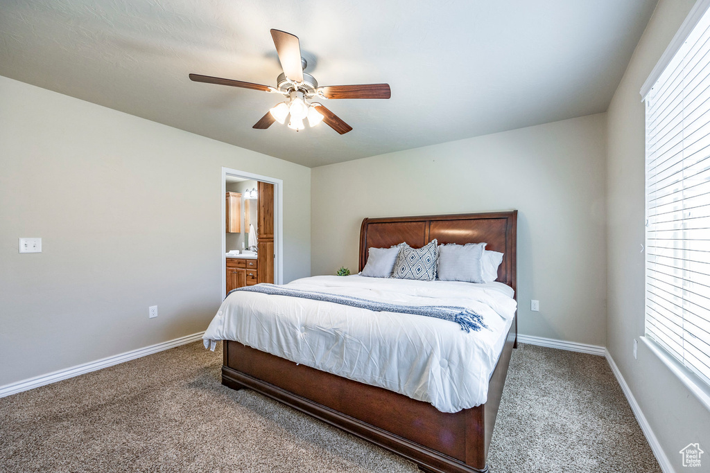 Carpeted bedroom with ceiling fan and connected bathroom