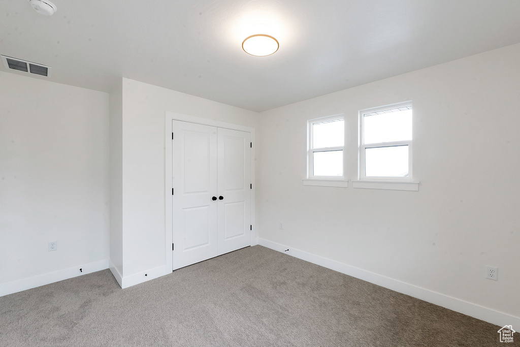 Unfurnished bedroom with carpet flooring and a closet