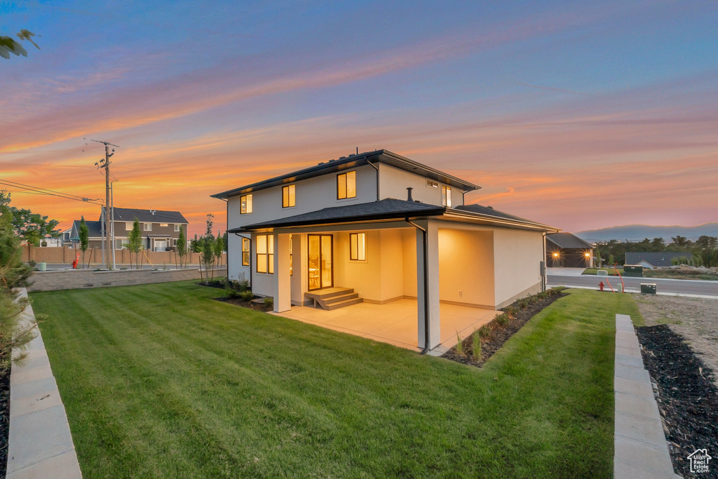 Back of house at dusk featuring stucco siding and a patio