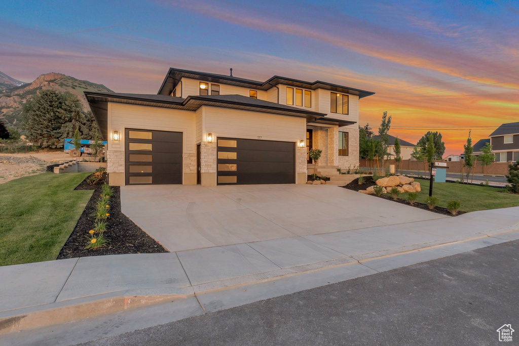 Contemporary house featuring a garage, a lawn, driveway, and a mountain view