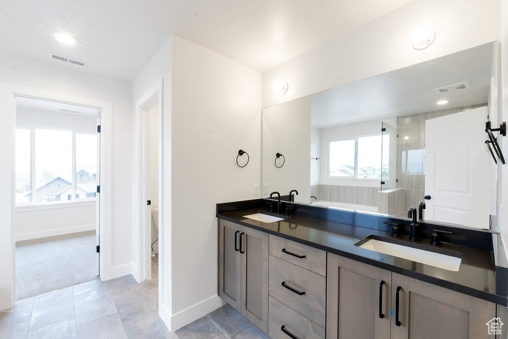 Bathroom featuring vanity, toilet, walk in shower, and tile patterned flooring