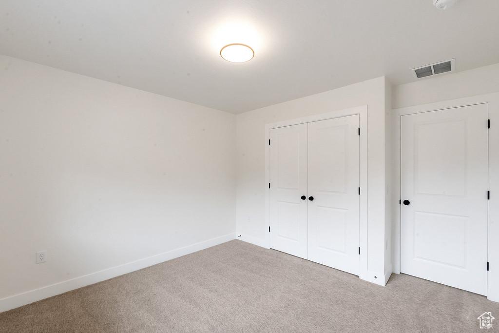 Unfurnished bedroom with a closet and light colored carpet