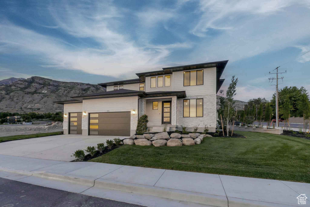 View of front of property with concrete driveway, a garage, a front yard, and a mountain view