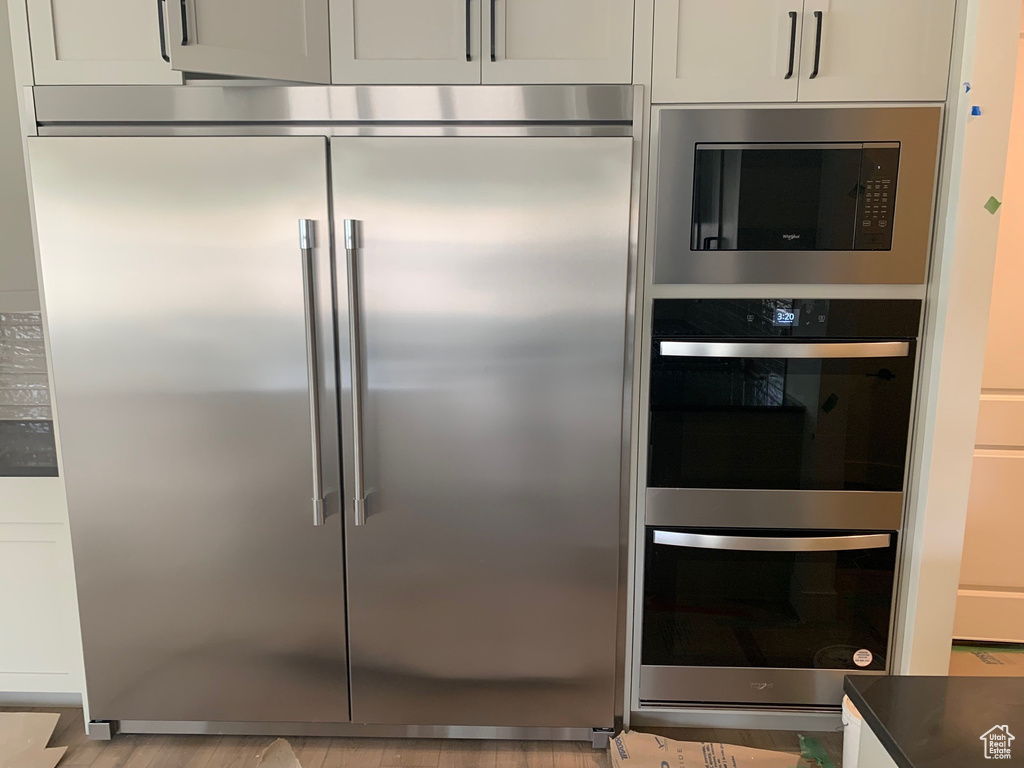 Kitchen featuring light hardwood / wood-style flooring, white cabinets, and built in appliances