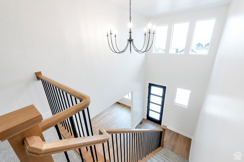 Staircase with hardwood / wood-style flooring and an inviting chandelier