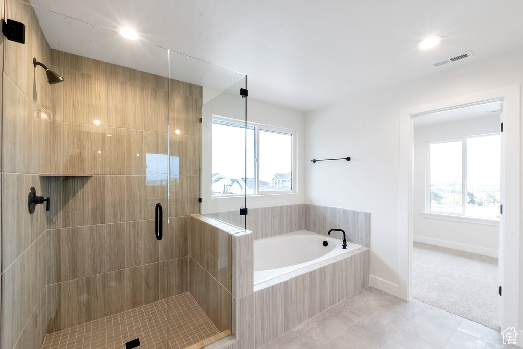 Bathroom featuring a wealth of natural light, separate shower and tub, and tile patterned floors