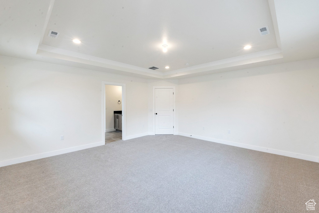 Carpeted spare room featuring a tray ceiling