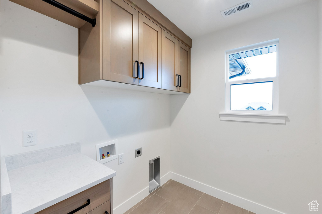 Clothes washing area with electric dryer hookup, washer hookup, and cabinets