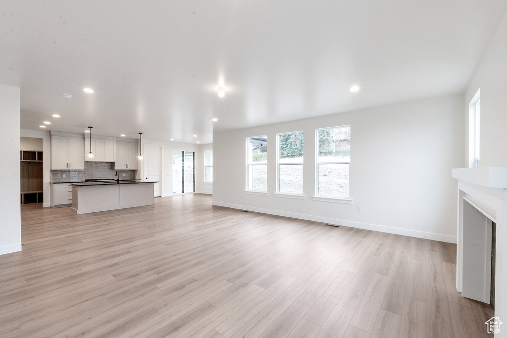 Unfurnished living room with light hardwood / wood-style flooring and sink