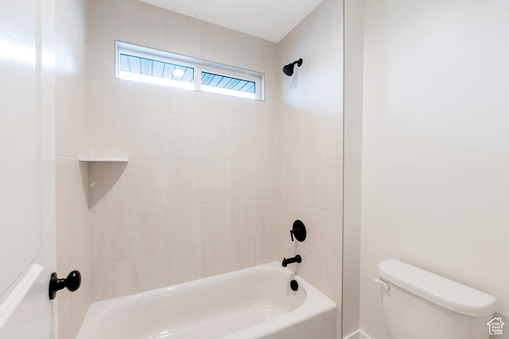 Bathroom with toilet and tiled shower / bath combo