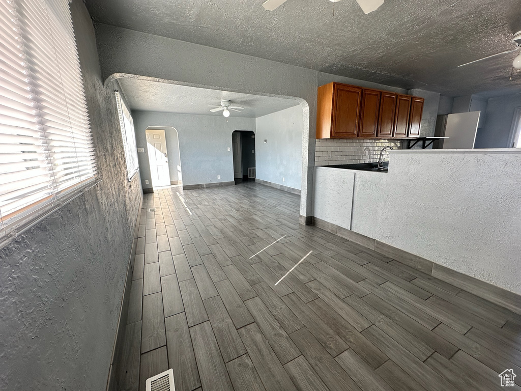 Interior space with sink, backsplash, light hardwood / wood-style flooring, and a textured ceiling