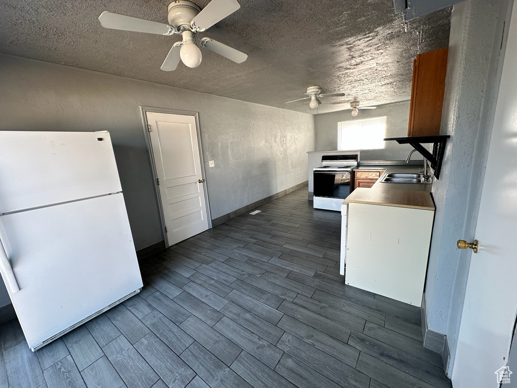 Kitchen featuring white appliances, hardwood / wood-style flooring, a textured ceiling, and ceiling fan