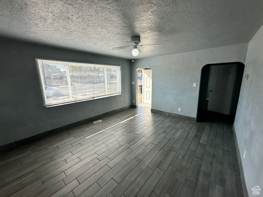 Empty room with ceiling fan, wood-type flooring, and a textured ceiling