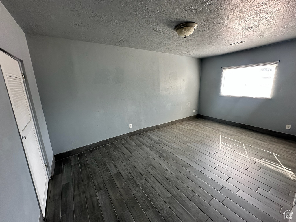 Spare room featuring wood-type flooring and a textured ceiling