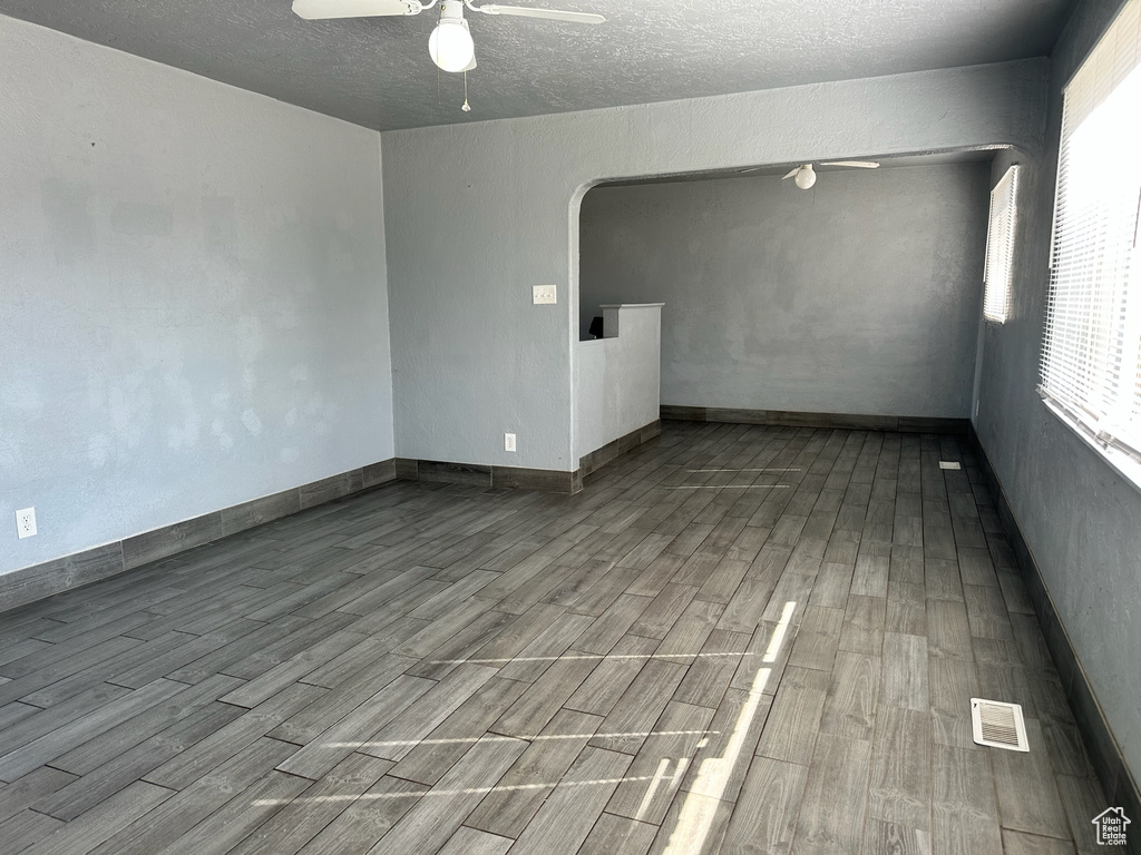 Empty room featuring ceiling fan, light hardwood / wood-style flooring, and a textured ceiling