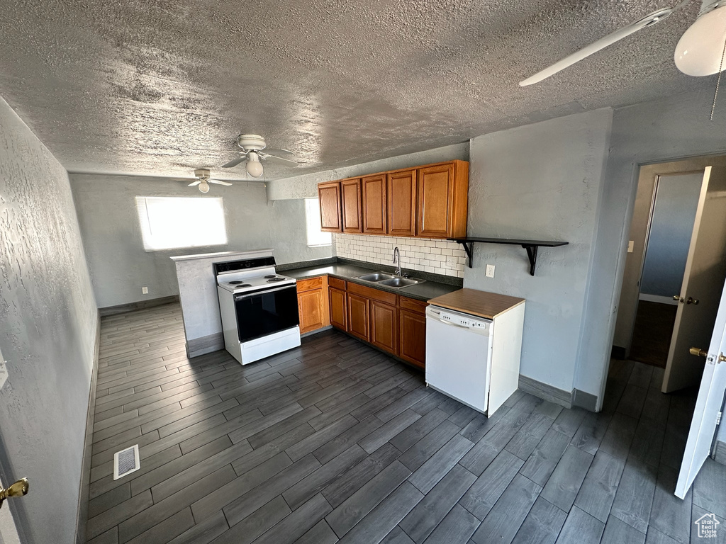 Kitchen with white appliances, sink, dark hardwood / wood-style floors, and a textured ceiling