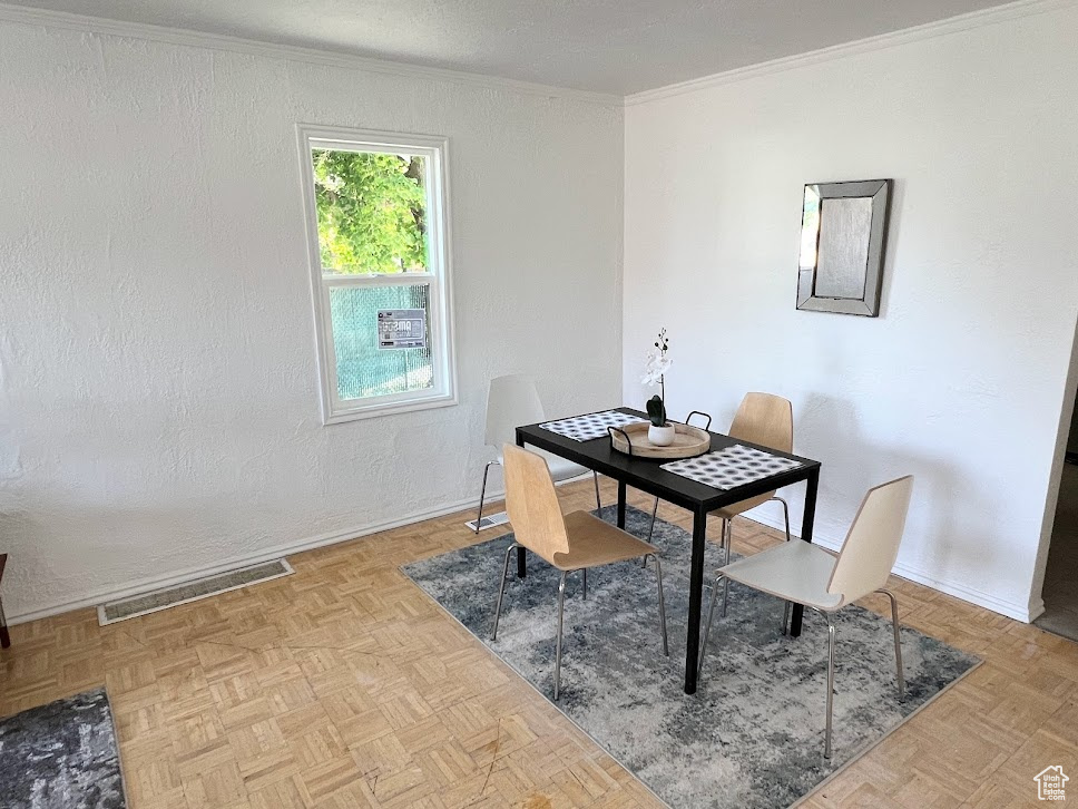 Dining area featuring ornamental molding and light parquet floors