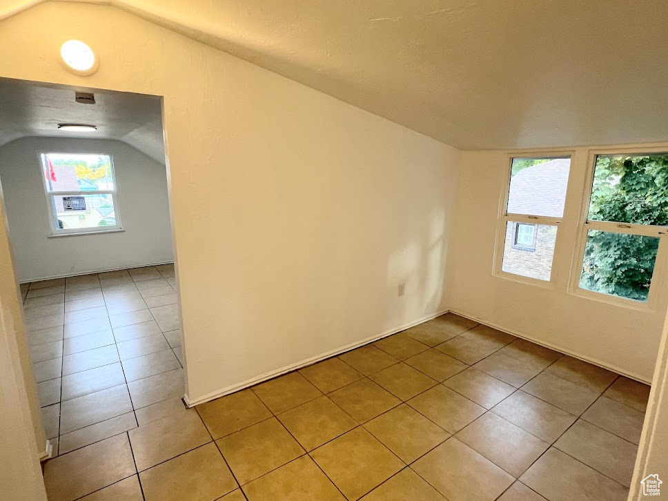 Tiled spare room with vaulted ceiling