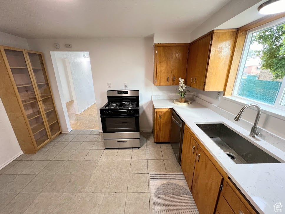 Kitchen with stainless steel appliances, sink, and light tile patterned floors