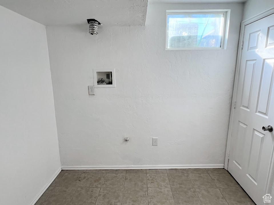 Clothes washing area with washer hookup and light tile patterned floors