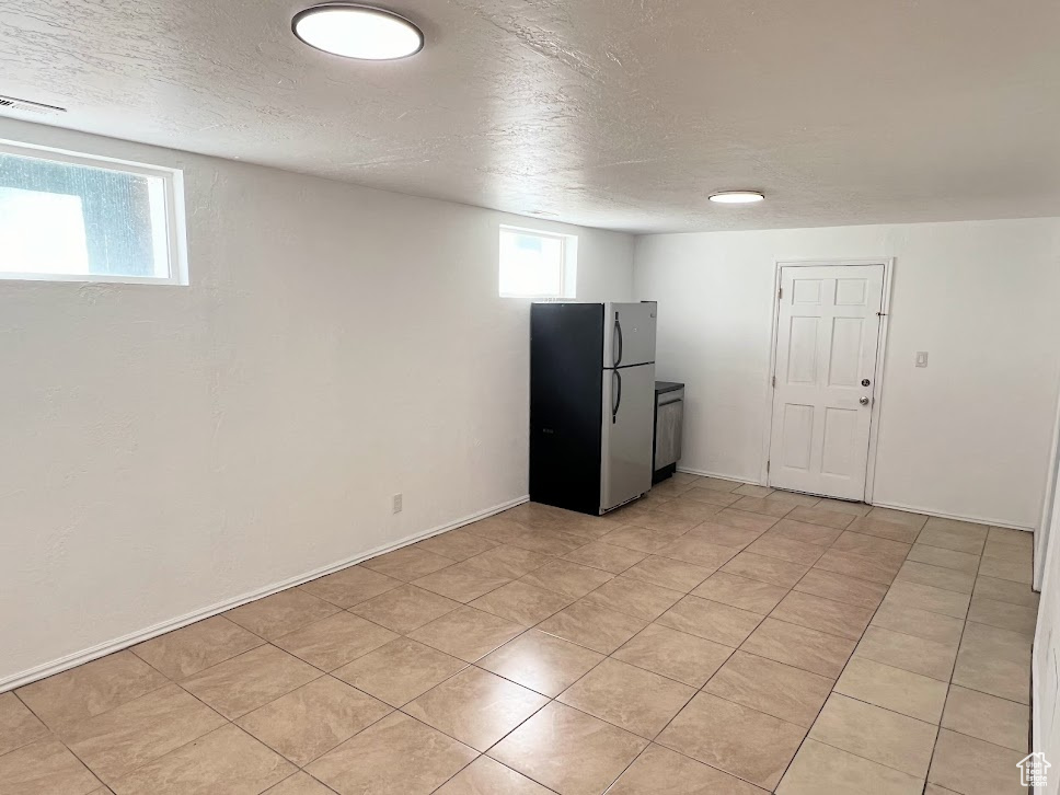 Basement featuring stainless steel refrigerator and a textured ceiling