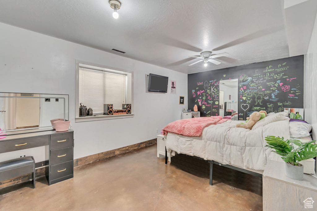 Bedroom with a textured ceiling, ceiling fan, and concrete flooring