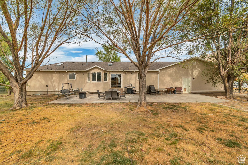 Rear view of property with a lawn and a patio