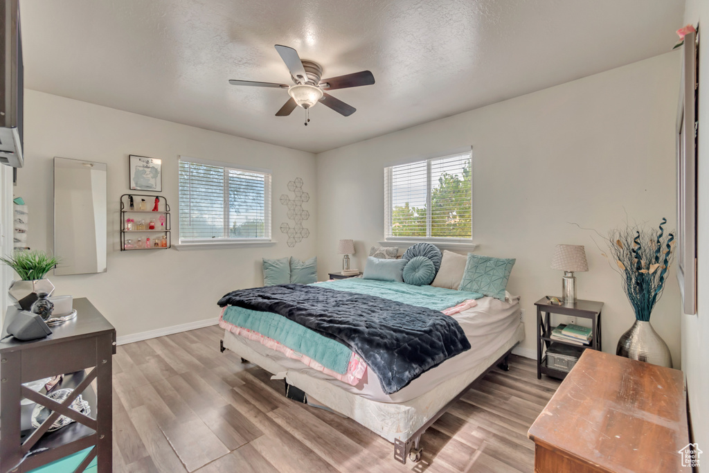 Bedroom featuring a textured ceiling, light wood-type flooring, and ceiling fan