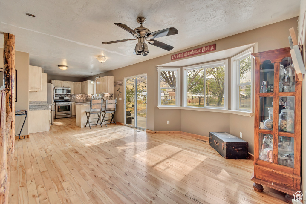 Unfurnished living room with ceiling fan, light hardwood / wood-style floors, and a textured ceiling