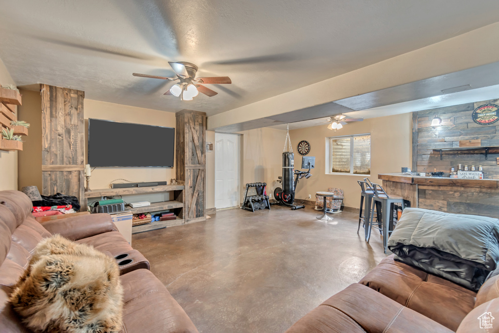 Living room featuring ceiling fan and concrete flooring