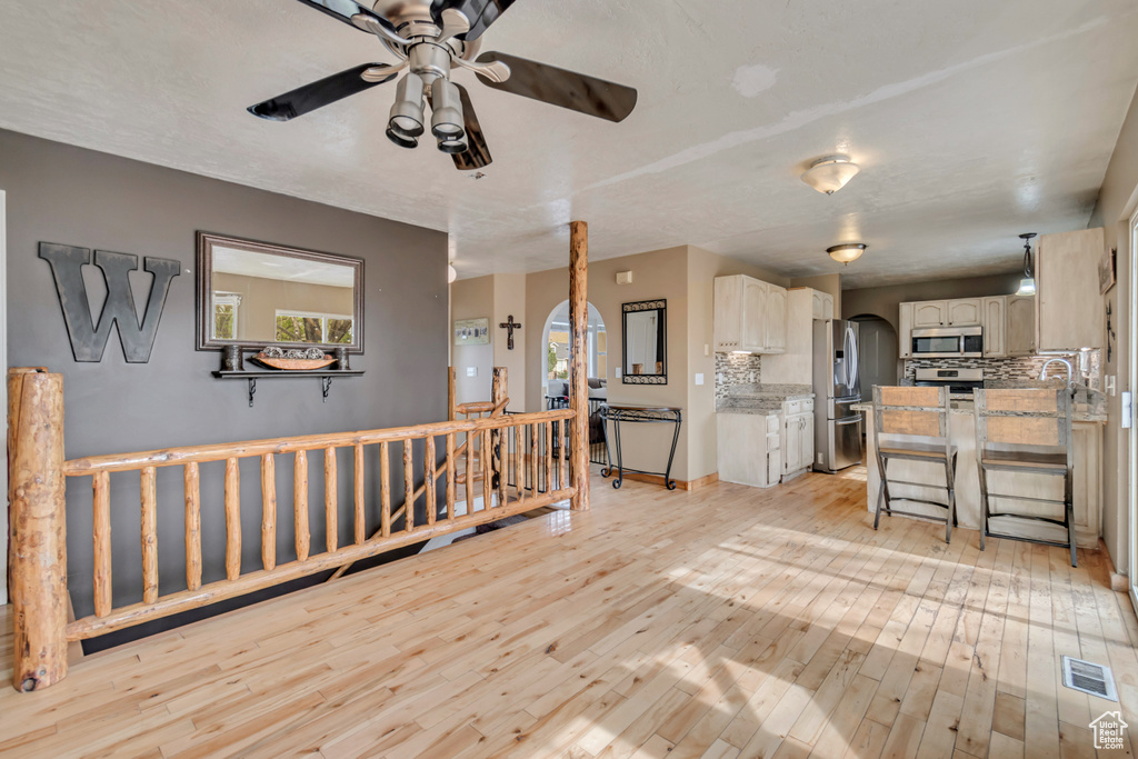 Living room with ceiling fan and light hardwood / wood-style flooring