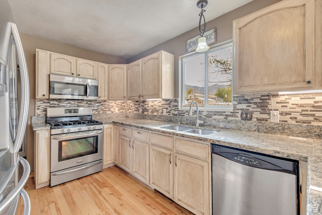 Kitchen with light brown cabinets, appliances with stainless steel finishes, sink, and light wood-type flooring