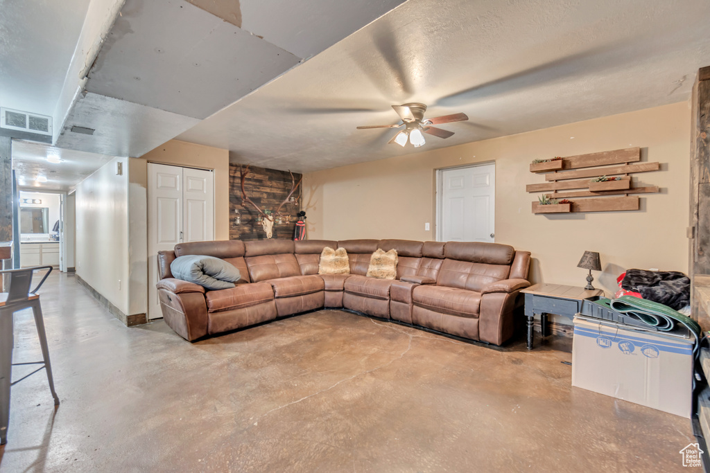 Living room with ceiling fan and concrete flooring