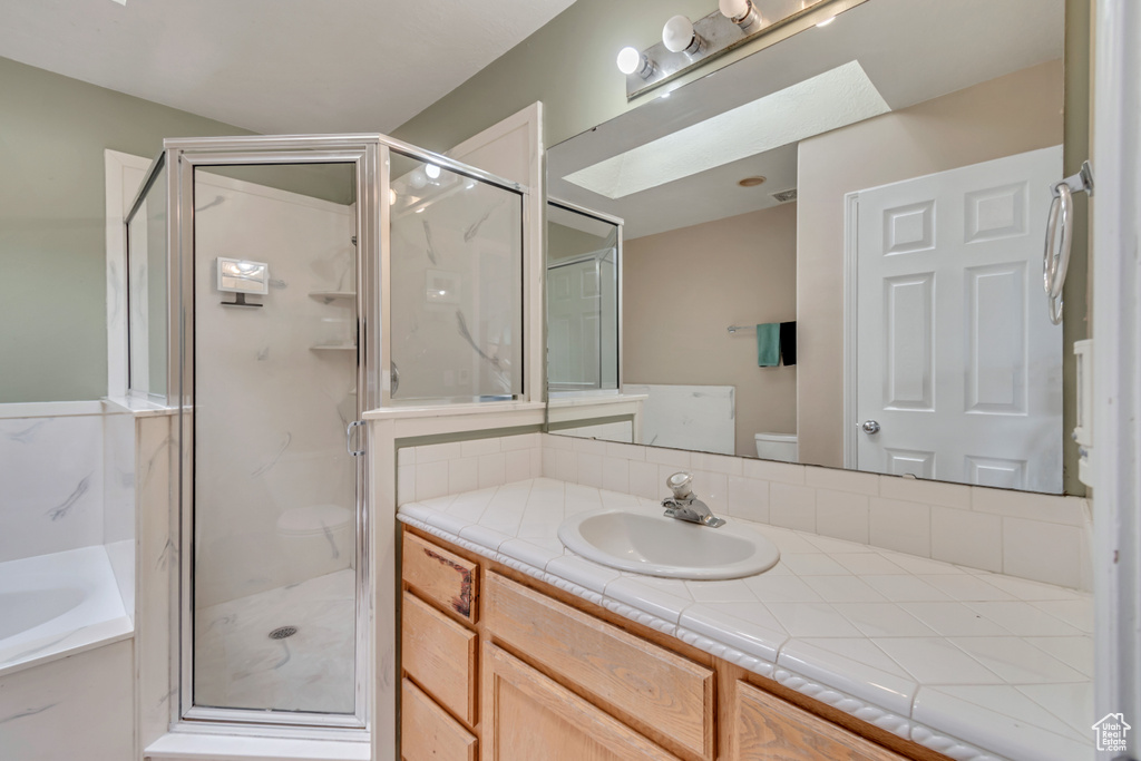 Full bathroom featuring a skylight, vanity, toilet, and independent shower and bath