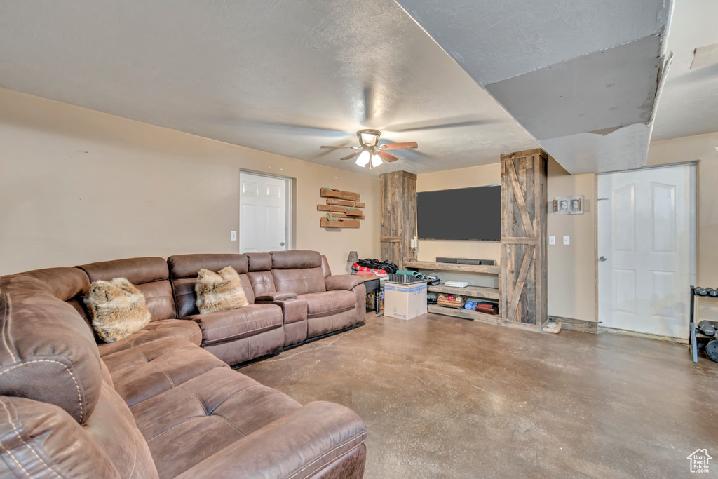 Living room featuring ceiling fan, a textured ceiling, and concrete floors