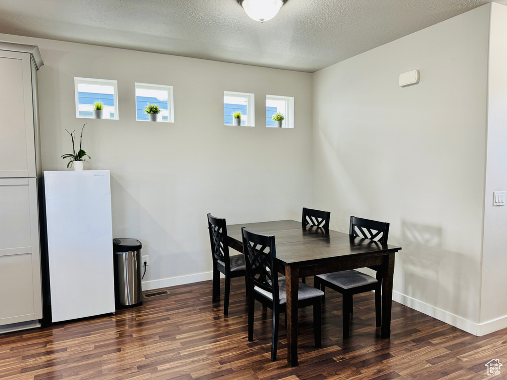 Dining room featuring dark hardwood / wood-style flooring and a textured ceiling