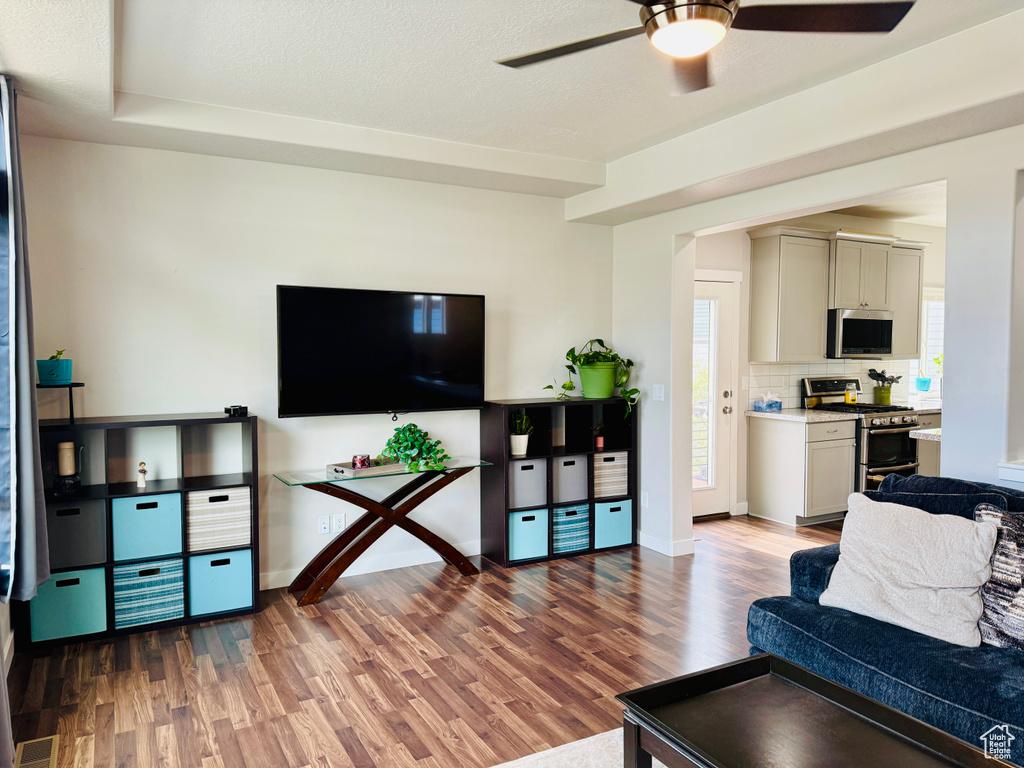 Living room featuring wood-type flooring, a textured ceiling, and ceiling fan