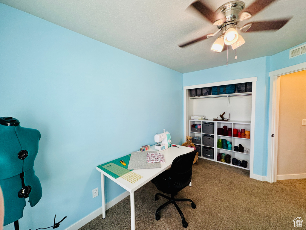 Carpeted office space with a textured ceiling and ceiling fan