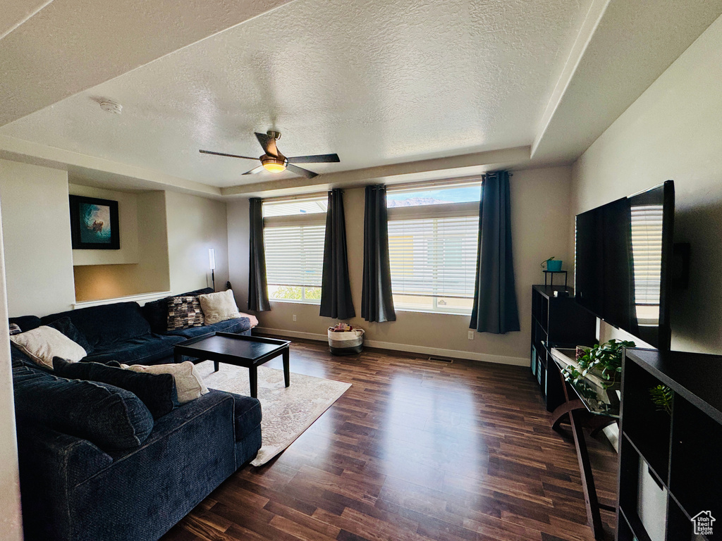 Living room with a textured ceiling, ceiling fan, and dark hardwood / wood-style flooring