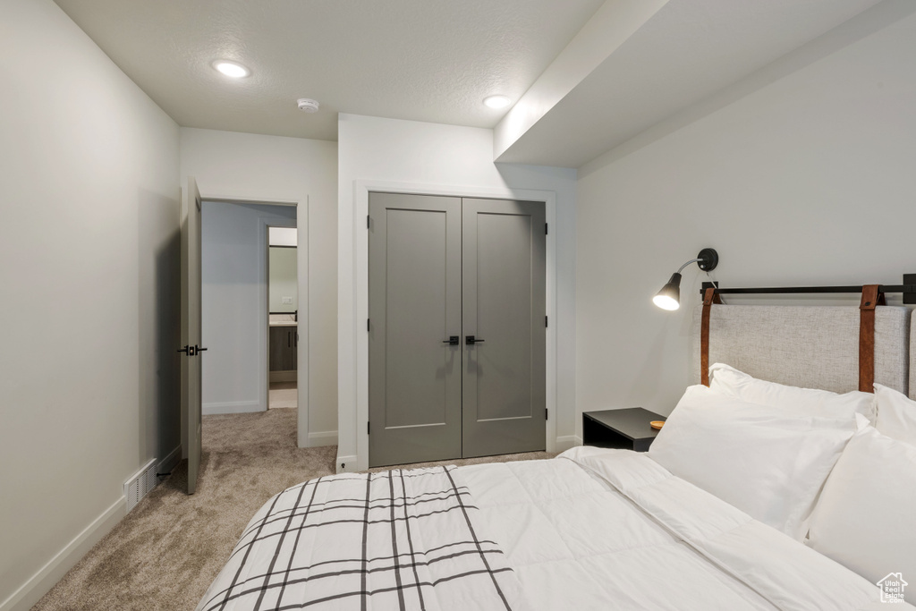 Bedroom with light carpet, a textured ceiling, and a closet