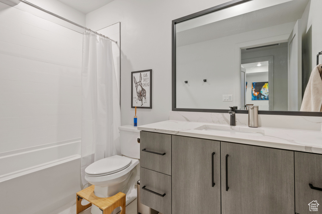 Full bathroom featuring toilet, shower / bath combo with shower curtain, and vanity