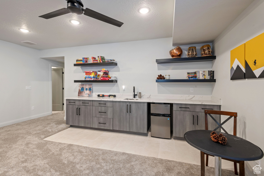 Bar featuring light carpet, ceiling fan, sink, and a textured ceiling