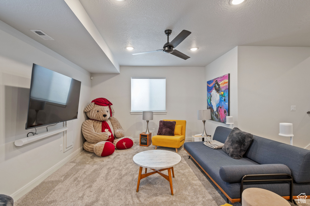 Living room with ceiling fan, carpet, and a textured ceiling