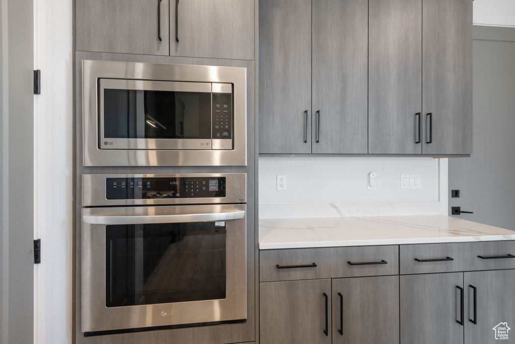 Kitchen with light stone counters, stainless steel appliances, and gray cabinetry