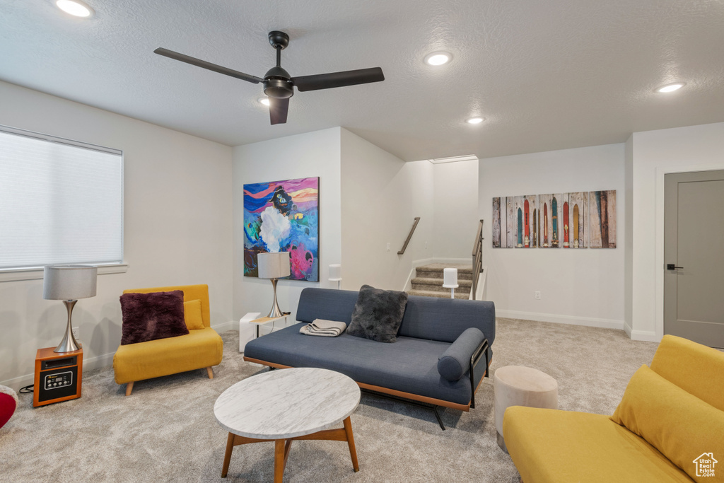 Living room featuring ceiling fan, carpet floors, and a textured ceiling