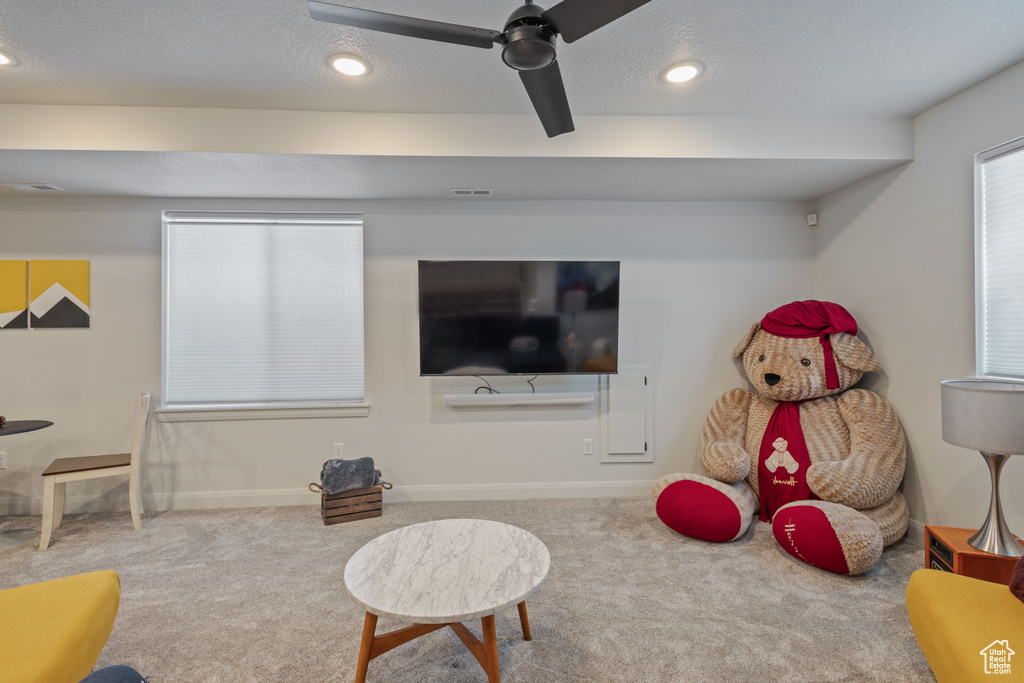 Interior space with ceiling fan, a textured ceiling, and carpet flooring