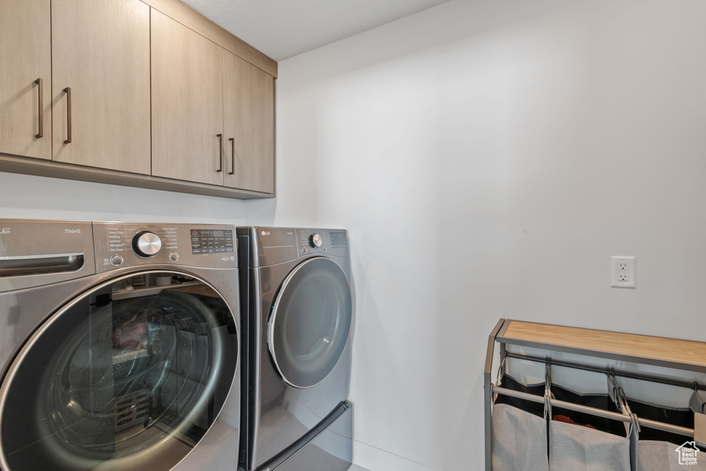 Washroom featuring washing machine and clothes dryer and cabinets