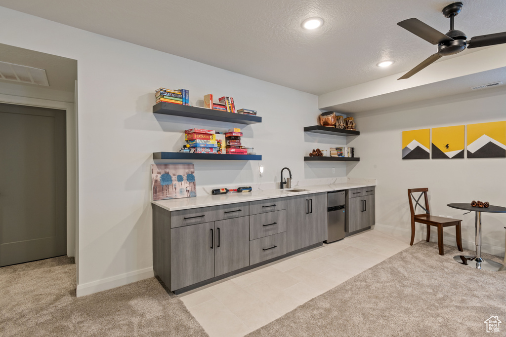 Bar featuring ceiling fan, light colored carpet, a textured ceiling, and sink