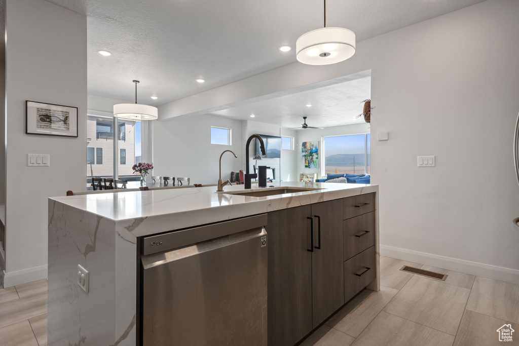 Kitchen featuring ceiling fan, pendant lighting, an island with sink, sink, and dishwasher